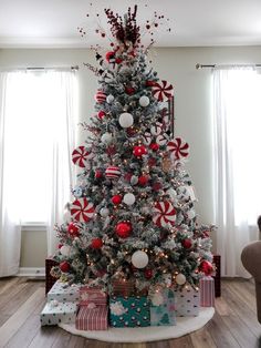 a decorated christmas tree in a living room with red and white ornaments on the top