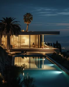 the pool is lit up at night with palm trees in the foreground and an ocean view behind it