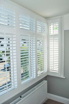 an empty room with white shutters and gray walls