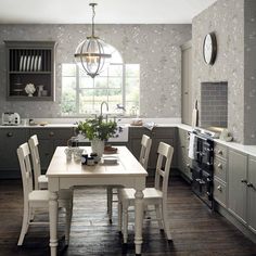 a dining room table and chairs in front of a window with flowers on the wall