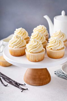 cupcakes with white frosting sitting on a cake plate