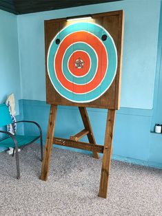 a wooden sign with an orange and blue target on it in a room next to a chair