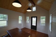 an empty room with wood floors and three lights hanging from the ceiling, along with two windows