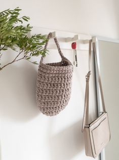 a crocheted bag hanging on the wall next to a purse