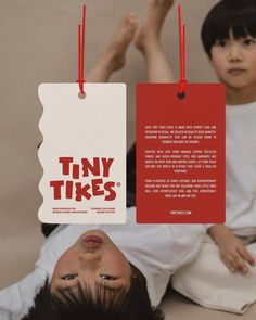 two children are laying on the floor with tiny tags attached to them