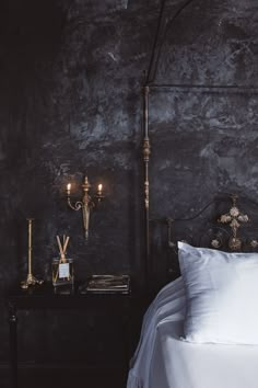 a bed sitting next to a night stand with two candles on it