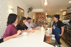 a group of people sitting at a counter in a coffee shop talking to each other