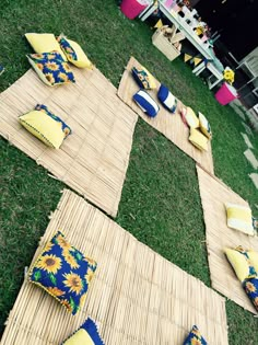 an outdoor lounge set up with sunflowers and pillows on the grass in front of a stage