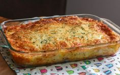 a casserole dish with cheese and herbs in it on a colorful table cloth