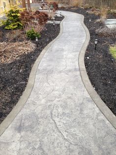 a walkway is lined with black mulch and gravel, leading to the front door