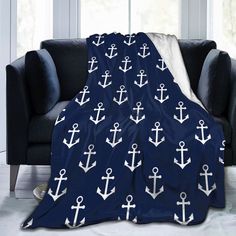 an anchor pattern on a blue blanket is displayed in front of a black couch and window