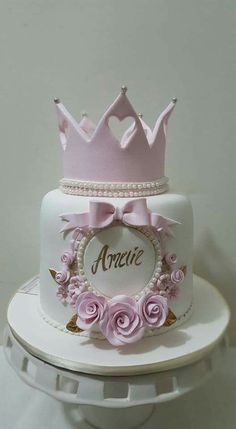 a white cake with pink roses and a crown on top