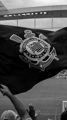 a black and white photo of people holding up a flag at a soccer game in the stadium