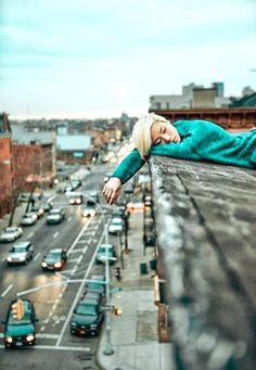 a woman laying on top of a roof next to traffic