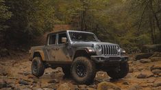 a jeep is driving through some rocks in the woods