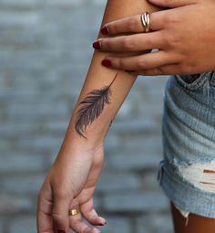 two people holding hands with tattoos on their arms and one has a feather tattoo on her arm