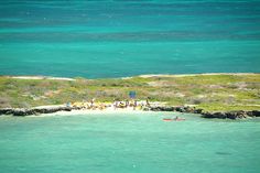 people are standing on the shore near an island