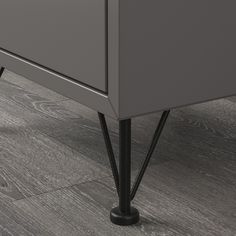 an image of a grey dresser with black legs and knobs on the bottom drawer