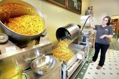 a woman standing in front of a large pot filled with corn kernels on top of a stove