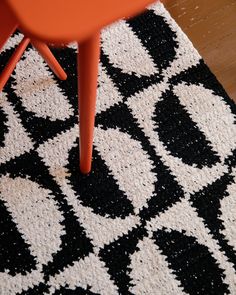 an orange chair sitting on top of a black and white rug