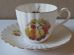 a cup and saucer with fruit painted on it