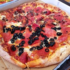 a pizza with olives and pepperoni in a box