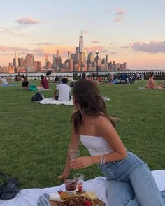 a woman sitting on top of a grass covered field next to a plate of food