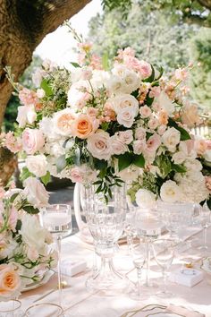 a table topped with lots of white and pink flowers next to glasses filled with wine