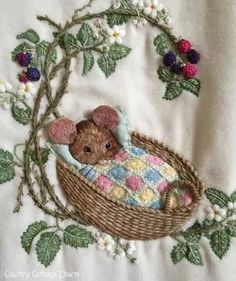 a teddy bear in a basket with flowers and vines around it on a white shirt