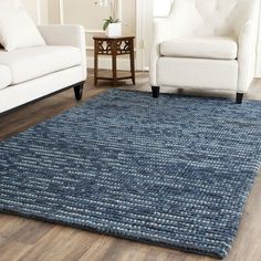 a living room with two white couches and a blue area rug on the floor