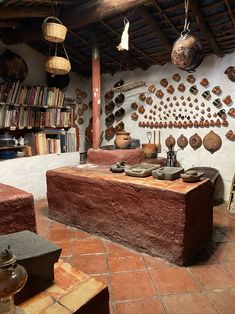 a room filled with lots of pots and pans hanging from the ceiling next to bookshelves