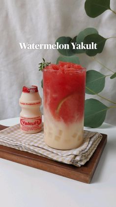 a watermelon yakult is sitting on a tray next to a bottle