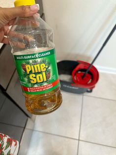 a person is holding a bottle of pine - soi cleaner in their hand while cleaning the floor