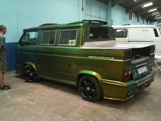 a green van parked inside of a garage next to another white van in the background