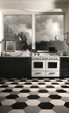 a black and white checkered floor in a kitchen with an oven, sink, and window