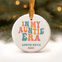 an ornament with the words in my auntie era on it hanging from a christmas tree