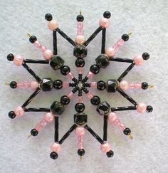 a snowflake made out of black and pink beaded beads on a white surface