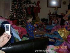 a person holding a cell phone in front of a christmas tree with presents on it