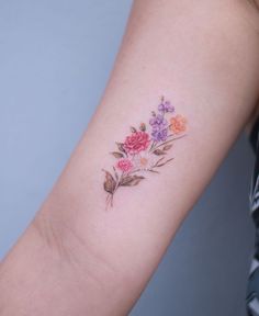 a woman's arm with flowers and leaves on the left side of her arm