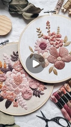 three embroidery hoops with flowers on them next to some scissors and other crafting supplies