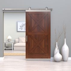 a living room with two vases on the floor and a barn door in the middle