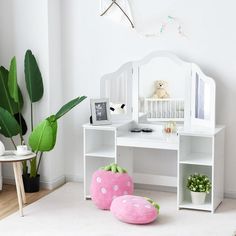 there is a white desk with two pink pillows on the floor and a stuffed animal in front of it