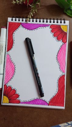 a notepad with a pen on top of it next to some markers and flowers