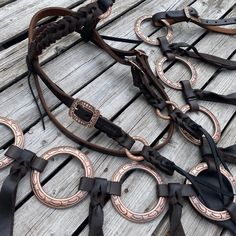 a bunch of different types of leathers on a wooden floor with metal rings attached to them