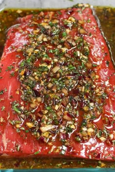 a piece of meat covered in sauce and garnished with chopped nuts on top