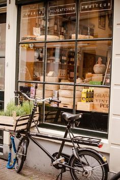 a bicycle is parked in front of a store window with plants on the windowsill