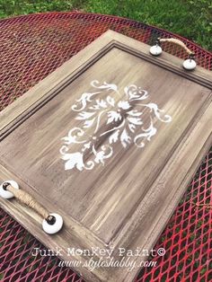 an old wooden tray with white stencils is sitting on top of a metal table