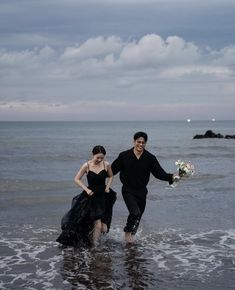 a man and woman are walking in the water at the beach with their bouquets