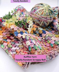 a ball of yarn sitting on top of a pile of crocheted material with the words ruffle yarn totally random scrappy ball