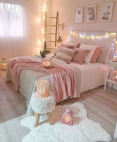 a bedroom decorated in pink and white with lights on the wall, bedding and rugs